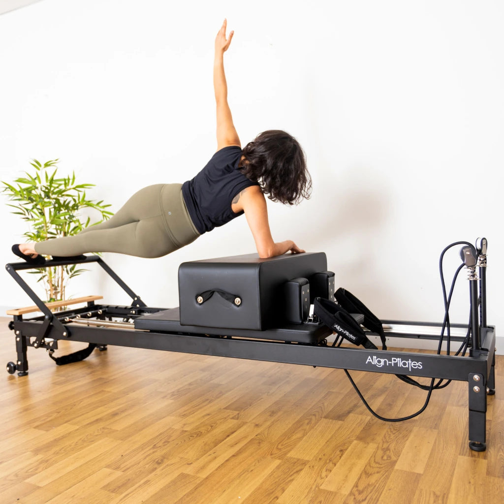 Frau trainiert auf der Align Pilates Curved Pro Sitting Box am Reformer